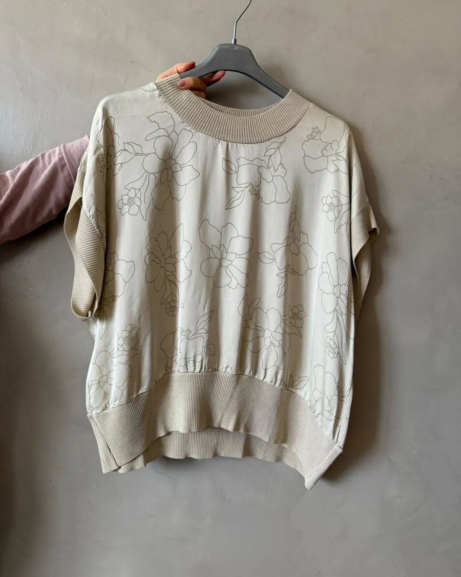 Remera estampada beige colgada en una percha